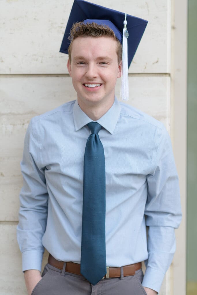 A man smiles wearing a graduation cap during his BYU senior portraits