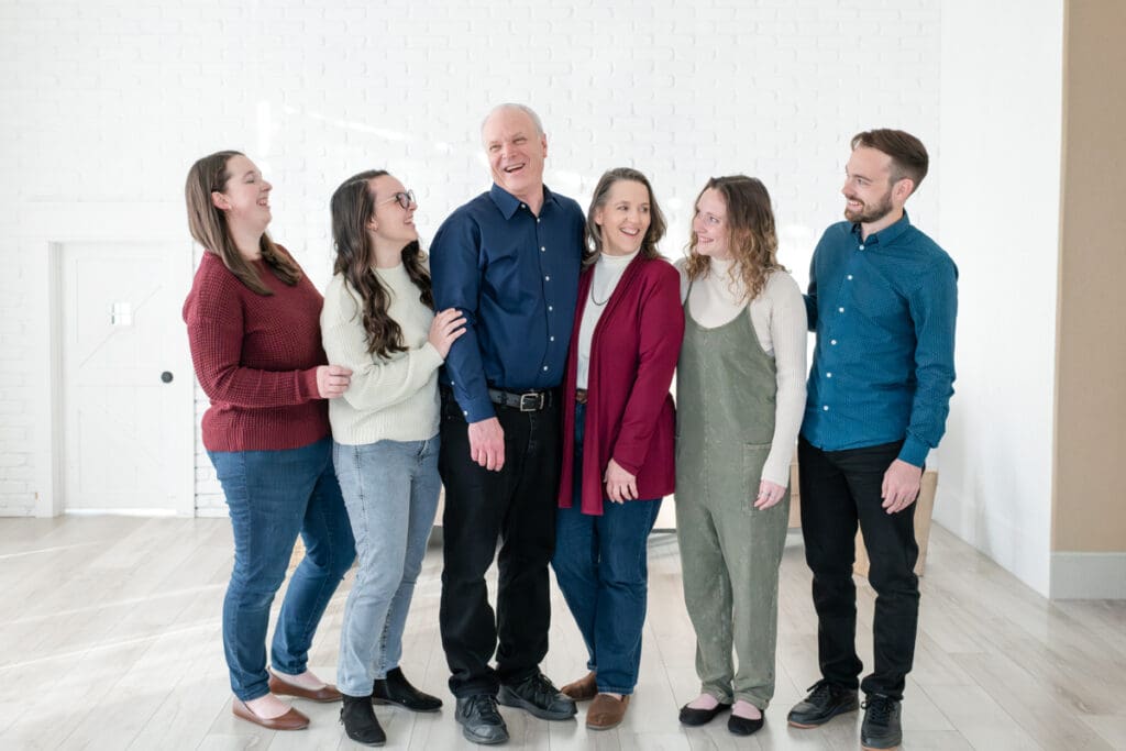 Family with adult children smiling at each other during a studio extended family session with Jodi Cornwall Photography.