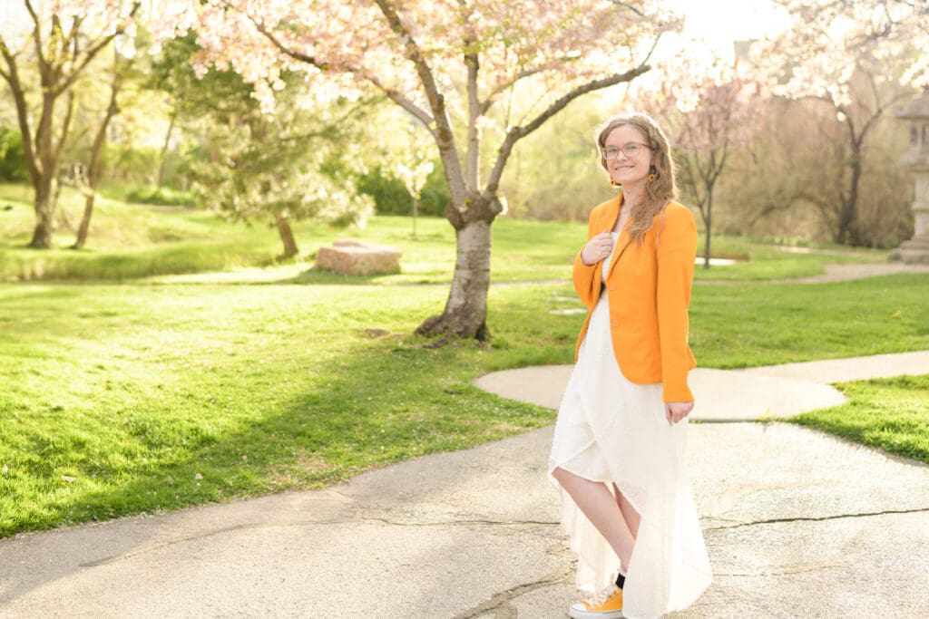 A graduating high school girl smiles during her colorful garden senior session with Salt Lake City photographer Jodi Cornwall Photography.