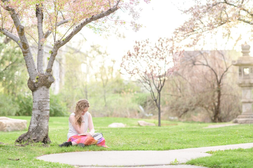 A graduating high school girl reads during her colorful garden senior session with Salt Lake City photographer Jodi Cornwall Photography.