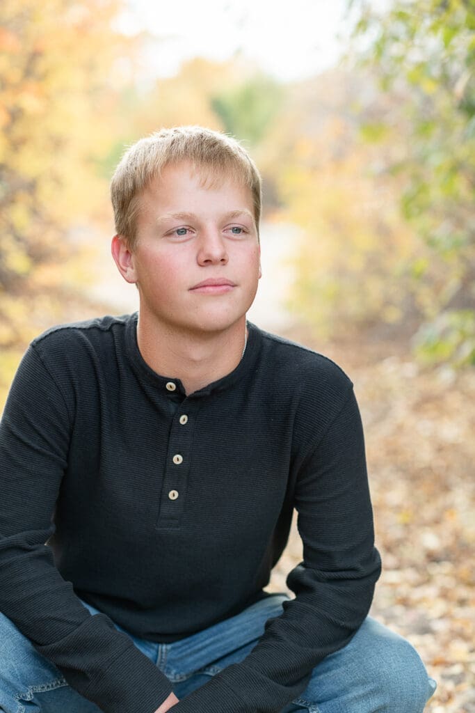High school senior boy smiles in the fall leaves