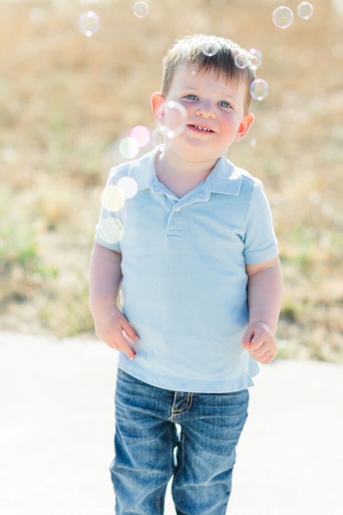 Little boy smiling while bubbles swirl around him