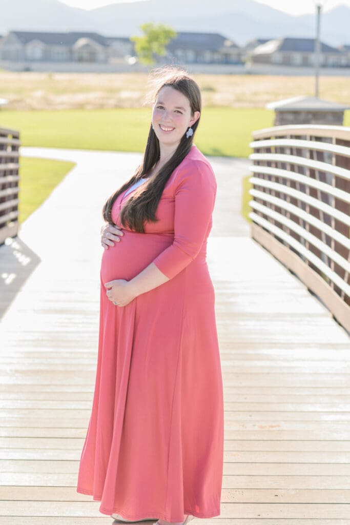 pregnant mom smiling on a bridge