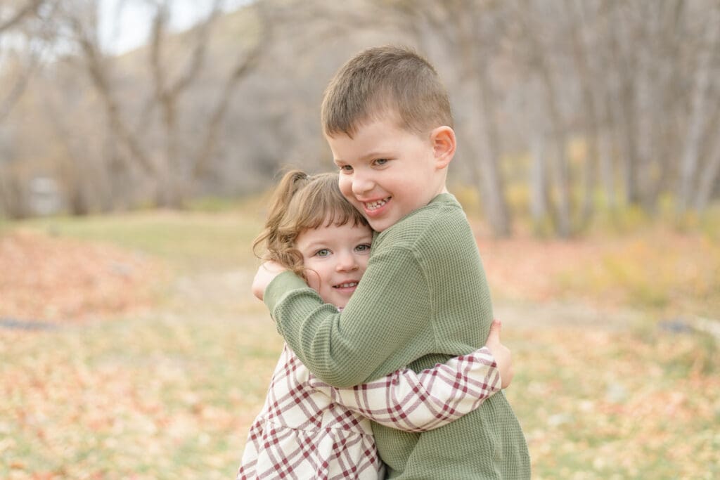 Brother and sister hugging in the fall leaves. Canyon Fall family Session