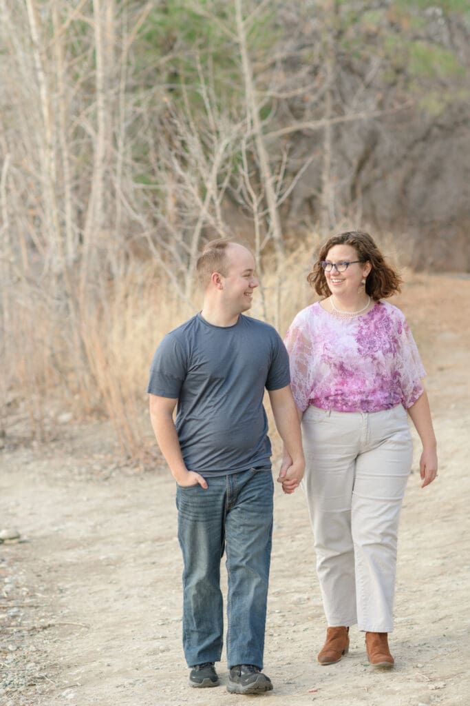 A couple holds hands and walks together during their joyful spring engagement session with Salt Lake photographer Jodi Cornwall Photography.