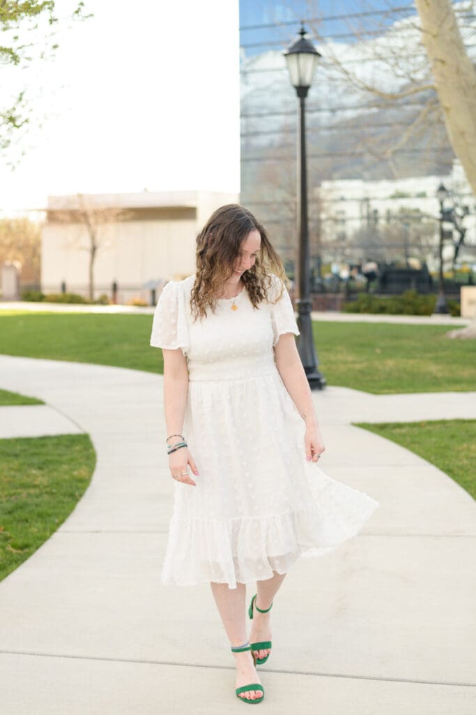 A woman smiles as she walks down a path during her joyful spring downtown senior session with Jodi Cornwall Photography