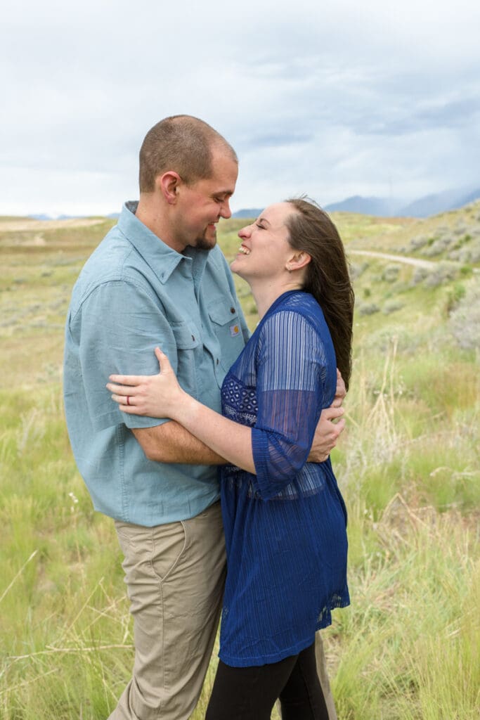 Married couple laughing in a field during a spring family photoshoot with Salt Lake Photographer Jodi Cornwall Photography.