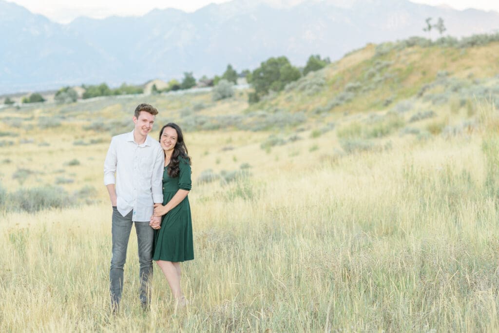 Engaged couple smiling in a field during their summer engagement session with Jodi Cornwall Photography