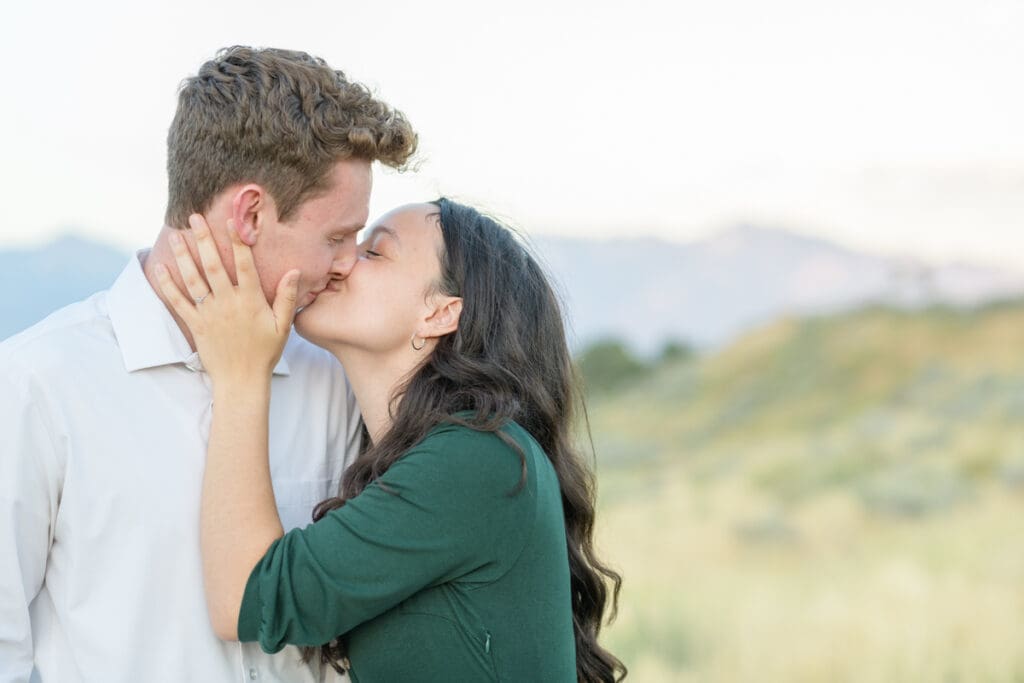 Engaged couple smiling in a field during their summer engagement session with Jodi Cornwall Photography