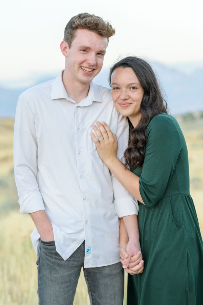 Engaged couple smiling in a field during their summer engagement session with Jodi Cornwall Photography