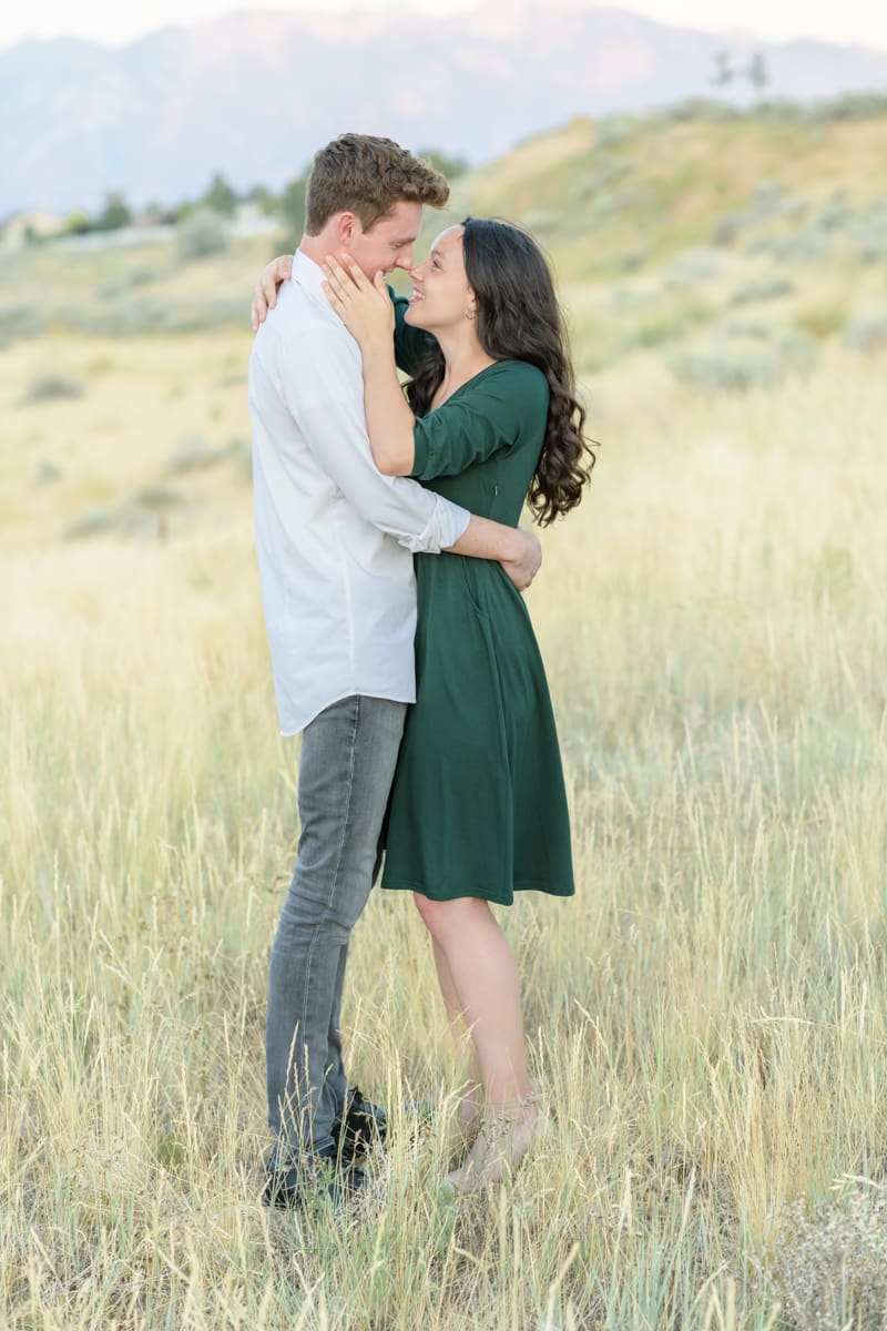 Engaged couple smiling in a field during their summer engagement session with Jodi Cornwall Photography