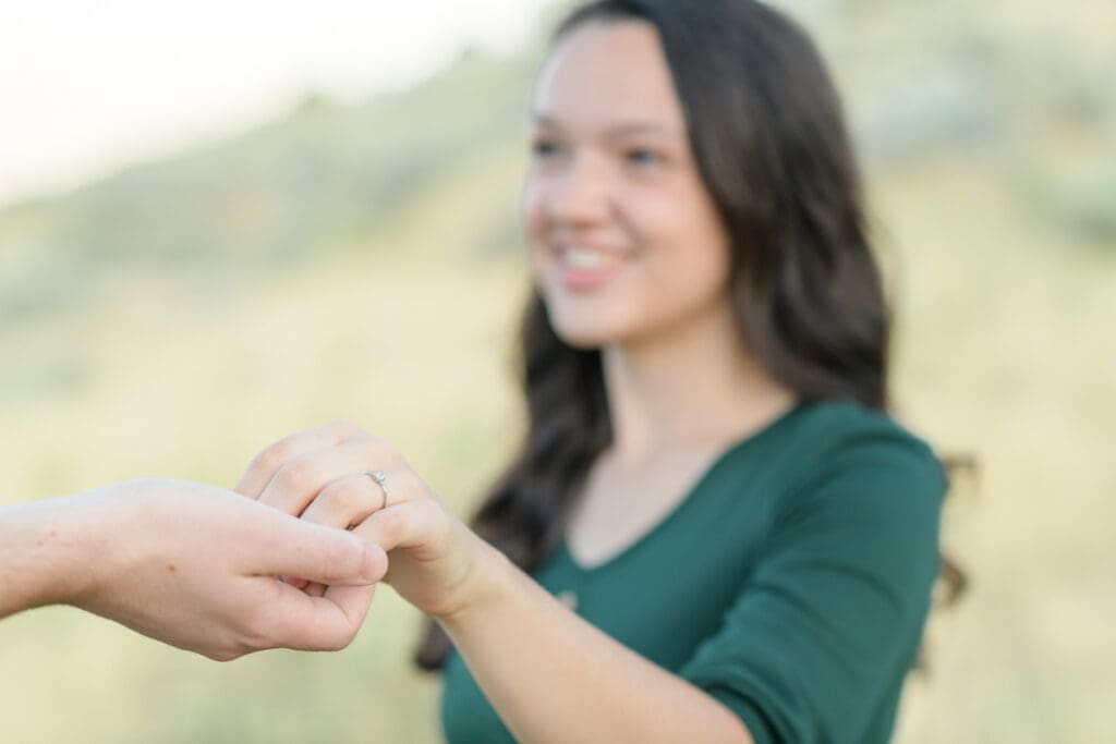 Engaged couple smiling in a field during their summer engagement session with Jodi Cornwall Photography