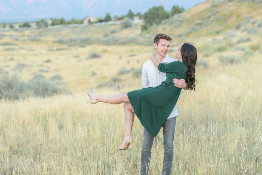 Engaged couple smiling in a field during their summer engagement session with Jodi Cornwall Photography