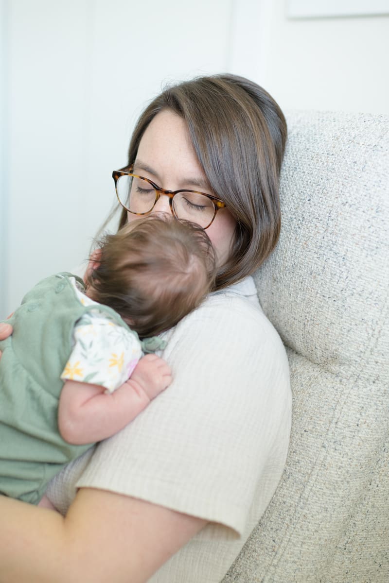 Mom snuggling with a newborn baby during a successful indoor photo session with Salt Lake City photographer, Jodi Cornwall.