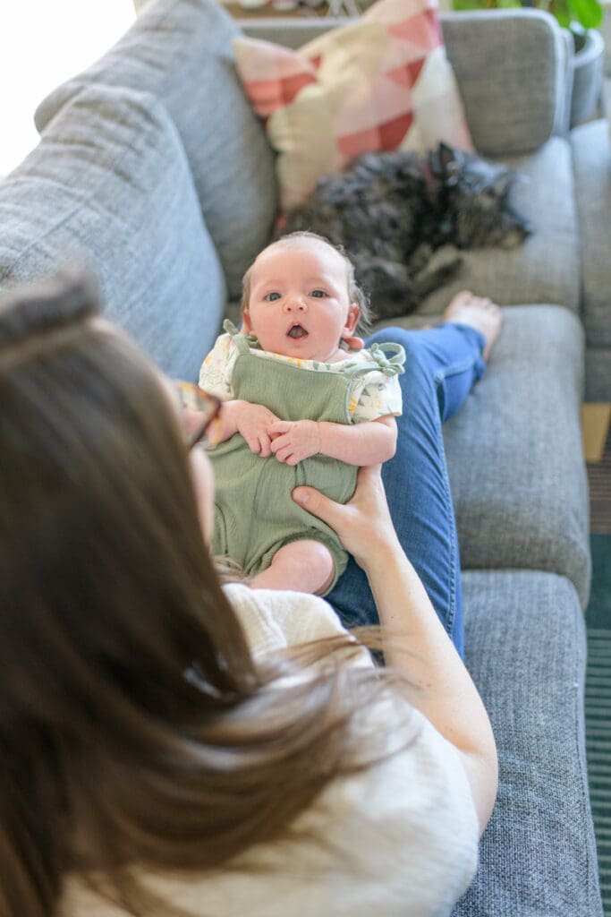 A baby snuggling with mom with a sleeping dog nearby during a successful indoor photo session with Salt Lake City photographer, Jodi Cornwall.