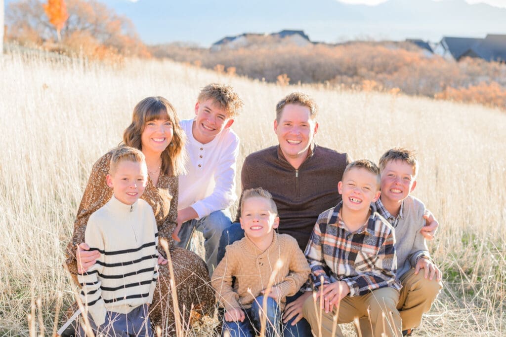 Parents and sons smiling in golden sunrise light.