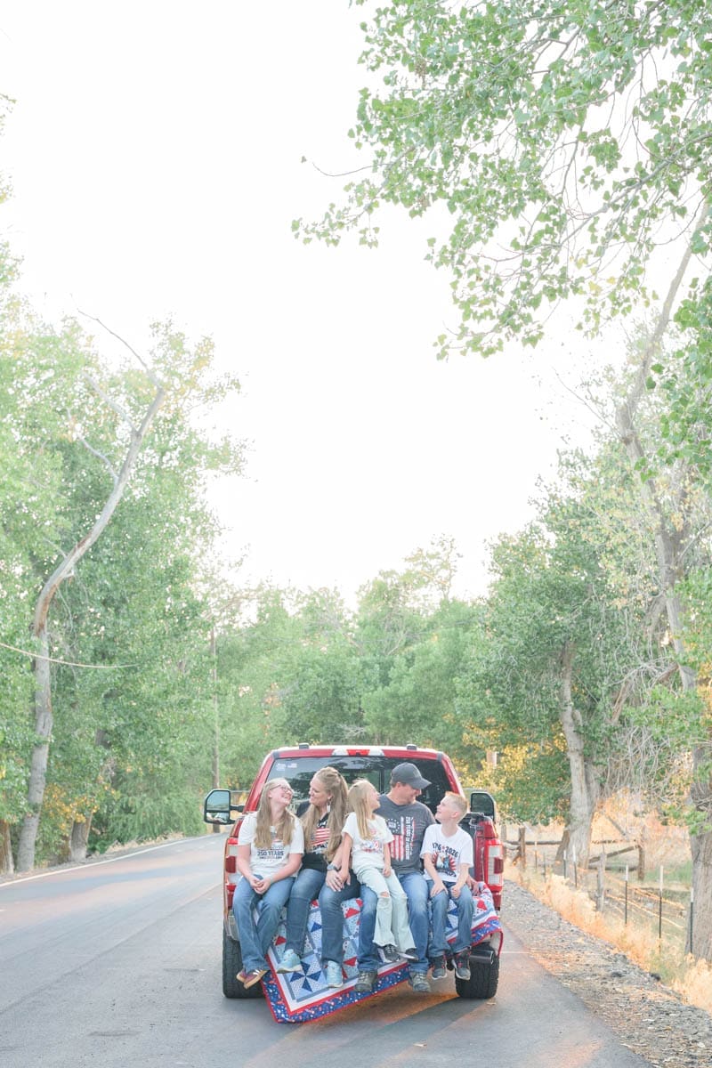 A family of five stands on a path and smiles at each other during family photos in Utah County.