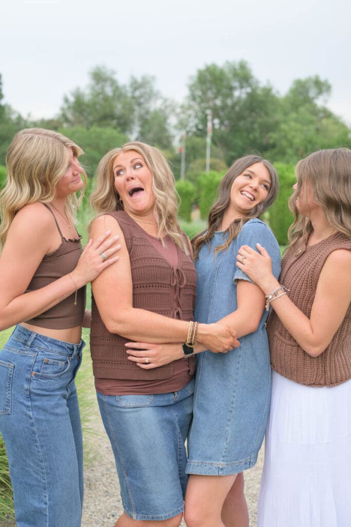 A mother and her three daughters laugh and hold each other close during an extended family photography session.
